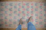View of the distressed texture and floral pattern in raspberry and teal on an Oushak runner.
