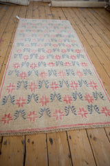 Angled perspective view of a distressed Oushak runner with repeating starburst blossoms.