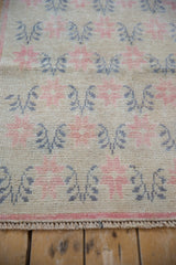 Close-up of the distressed Oushak's even wear, showing pale raspberry starburst blossoms and side cord.