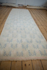 Distressed vintage Oushak runner displaying pale blue floral vines and short pile texture.