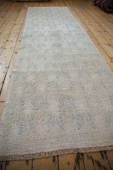 Close-up of vintage distressed Oushak runner texture with faded blue and rose floral motifs.