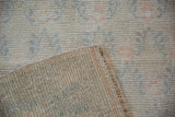 Distressed vintage Oushak rug: short pile, platinum, blue, rose, and intact selvage.
