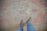 Evenly worn pile of a distressed Oushak runner with faded bubblegum pink and sand motifs.