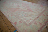 Angled view along the distressed Oushak runner, showing its soft pink and sand palette.