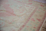 Detail of the low, even pile on a distressed vintage Oushak with soft pink and mint motifs.