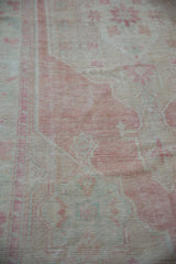 Faint foundation shows through the evenly worn, low pile of this vintage Oushak rug.