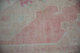 Distressed hand-knotted pile of a vintage Oushak rug showing even wear in soft pink, sand, and mint.