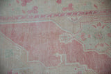 Evenly worn knot heads of a distressed Turkish Oushak rug in soft pink and beige.