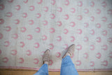 Low, even pile of a distressed Oushak rug with repeating dusty raspberry rose motifs.