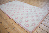 Angled perspective of a distressed Oushak rug with staggered rows of dusty rose tulip blossoms.