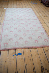 A full length perspective of the distressed Oushak rug showing the diagonal layout of tulip motifs.