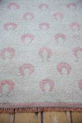 Evenly worn, hand-knotted pile of a vintage Oushak rug with raspberry rose tulip motifs.