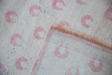 View of the vintage rug's back, showing the hand-knotted weave and secured side cord.