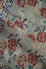 Distressed Oushak runner, showing folded pile texture with worn rose bouquets, muted red and teal.