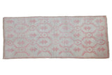 Vintage distressed Oushak runner with an allover floral pattern in pale raspberry red on an antique ivory field.