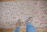 Close view of a vintage Oushak runner showing its distressed low-pile texture and pale raspberry red pattern.