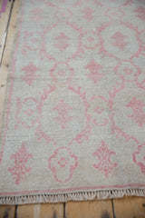 Distressed texture of a vintage Oushak runner showing low pile and pale red floral design.