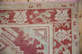 Meandering floral vine border in cochineal red and ivory on a distressed Turkish Oushak corner.