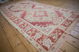 A low angle highlights the distressed texture of the vintage Oushak's red and ivory geometric patterns.