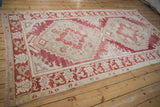 High-angle view of the vintage distressed Oushak carpet showing its red and ivory palette.