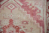 Hand-knotted texture showing even wear on a distressed Oushak with stepped cochineal red motifs.