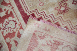 Folded corner of a distressed Oushak carpet revealing its hand-knotted foundation.