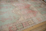 Distressed Oushak runner detail: mint green, raspberry red panels with scrolled vine pattern.