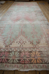 Vintage Oushak runner with distressed texture, faded mint green, raspberry, and beige geometric motifs.