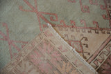 Distressed mint green Oushak pile with raspberry pattern and hand-knotted foundation.