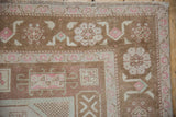 Oushak rug corner, distressed coffee brown field, blush, and pale green gul motifs.
