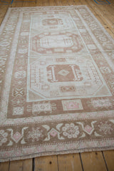 Distressed vintage Oushak rug detail: coffee brown, ivory, blush geometric borders and stylized blossoms.