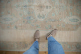 Worn pile of a distressed Oushak rug, showing cream, mint, and pale coffee patterns.
