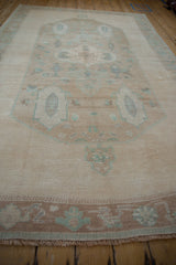 Distressed brown border of the vintage Oushak rug with cream fringe and pale green patterns.