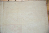 Distressed Dosemealti rug: platinum silver pile, faint blush rose geometric patterns, and fringed edge.