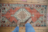 Distressed Oushak runner, showing worn pile, abrashed brick red field, and pale blue geometric patterns.