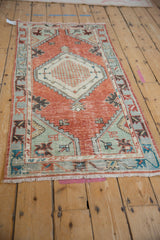 Distressed brick red Oushak rug corner with teal spandrel and geometric patterns.