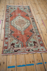Distressed brick red field and geometric teal spandrel on a vintage Oushak runner.
