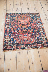 Tattered bottom edge and barber pole border design of a vintage Borchalou square rug.