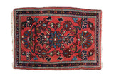 Vintage Lilihan rug mat with a pomegranate medallion on a deep blush field surrounded by a navy blue border.