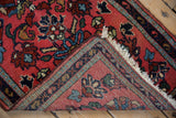 Folded corner of a vintage Lilihan rug reveals its hand-knotted foundation and deep blush floral pile.