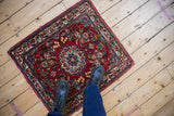 Scale shot of a vintage Qazvin mat with a scalloped floral medallion in cherry red.