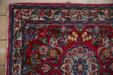 Traditional rose and vine border framing the cherry red floral field of a Persian Qazvin rug.