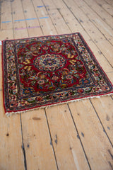 High-angle view of a vintage Qazvin mat showcasing its cherry red field and central medallion.