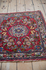 Angled view of a vintage Qazvin rug's floral design and cherry red, hand-knotted wool pile.