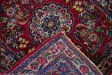 Detail of a vintage Persian rug's folded corner, showing the floral border and hand-knotted back.