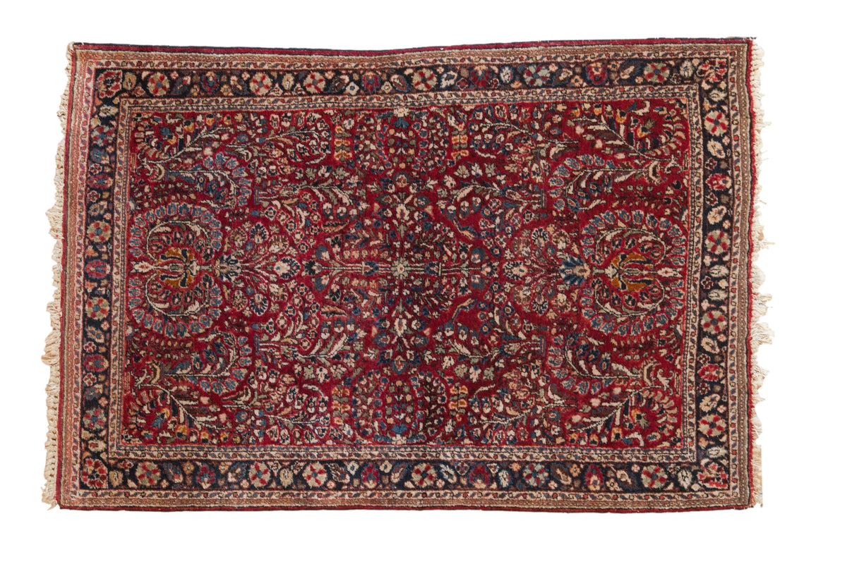 Vintage Sarouk rug with an allover floral spray pattern in cherry red, navy blue, and ivory.