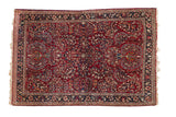 Vintage Sarouk rug with an allover floral spray pattern in cherry red, navy blue, and ivory.
