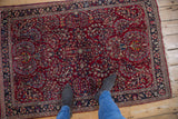 A personal perspective of the vintage Sarouk rug's texture and cherry red floral spray pattern.