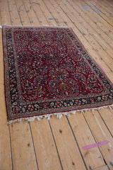 Vintage Sarouk rug from a high angle, showing the full cherry red and navy floral design.