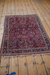 Perspective view of a vintage Sarouk rug's floral sprays and pinwheel border.